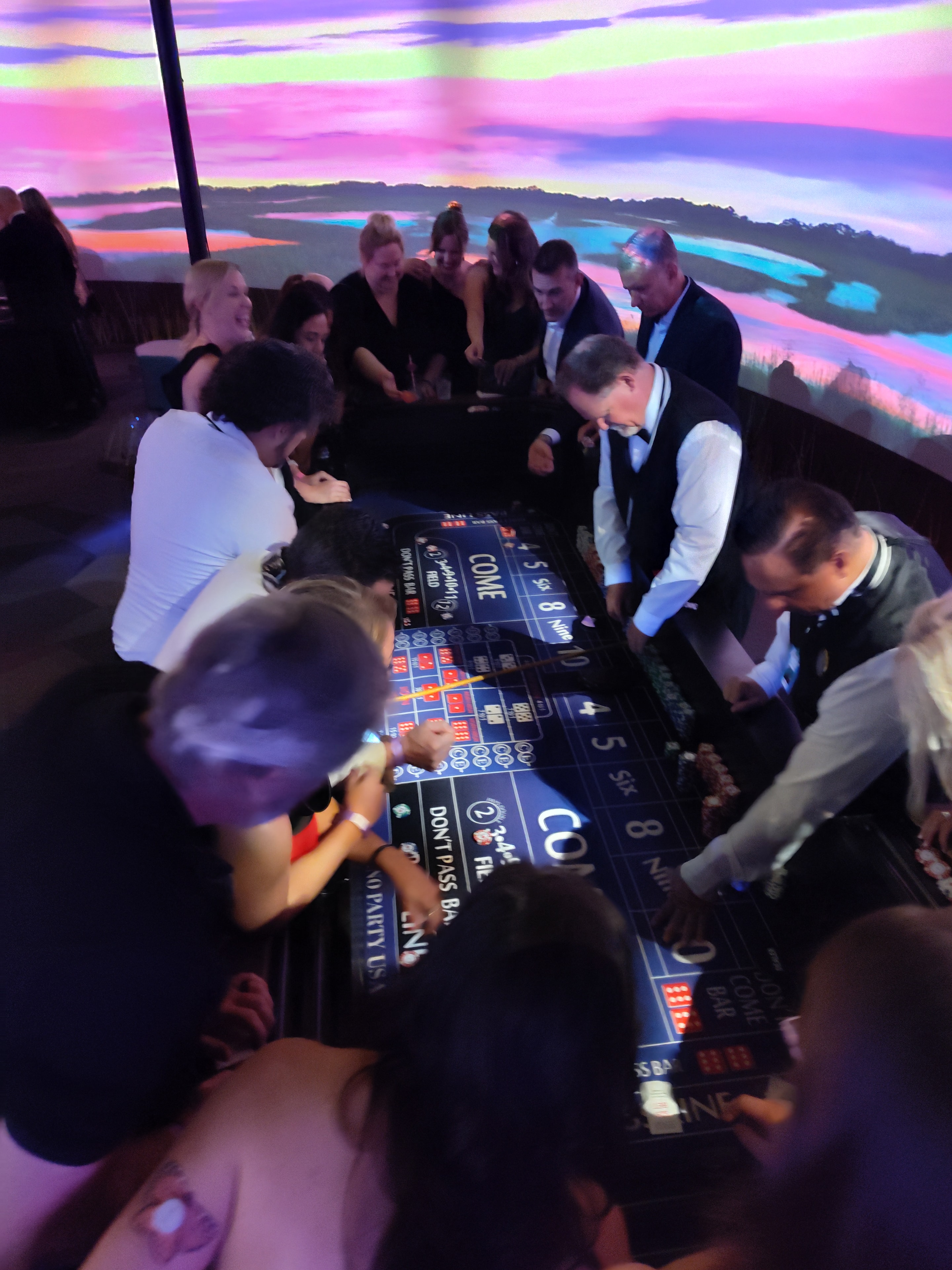 Guests and dealer at a blackjack table under colorful uplighting at a Stevensville Casino Party USA event