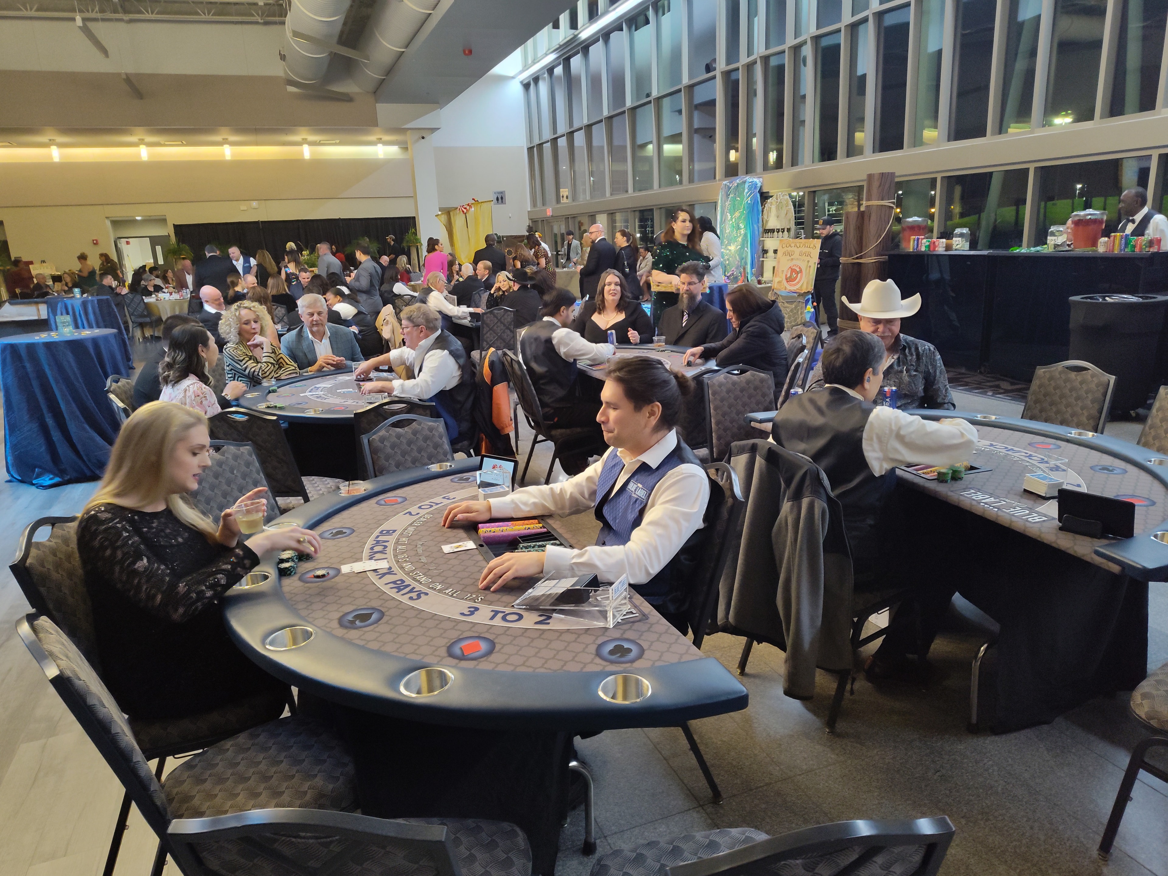 Wide-angle view of multiple Blue Label blackjack tables packed with guests at a Houston casino party event