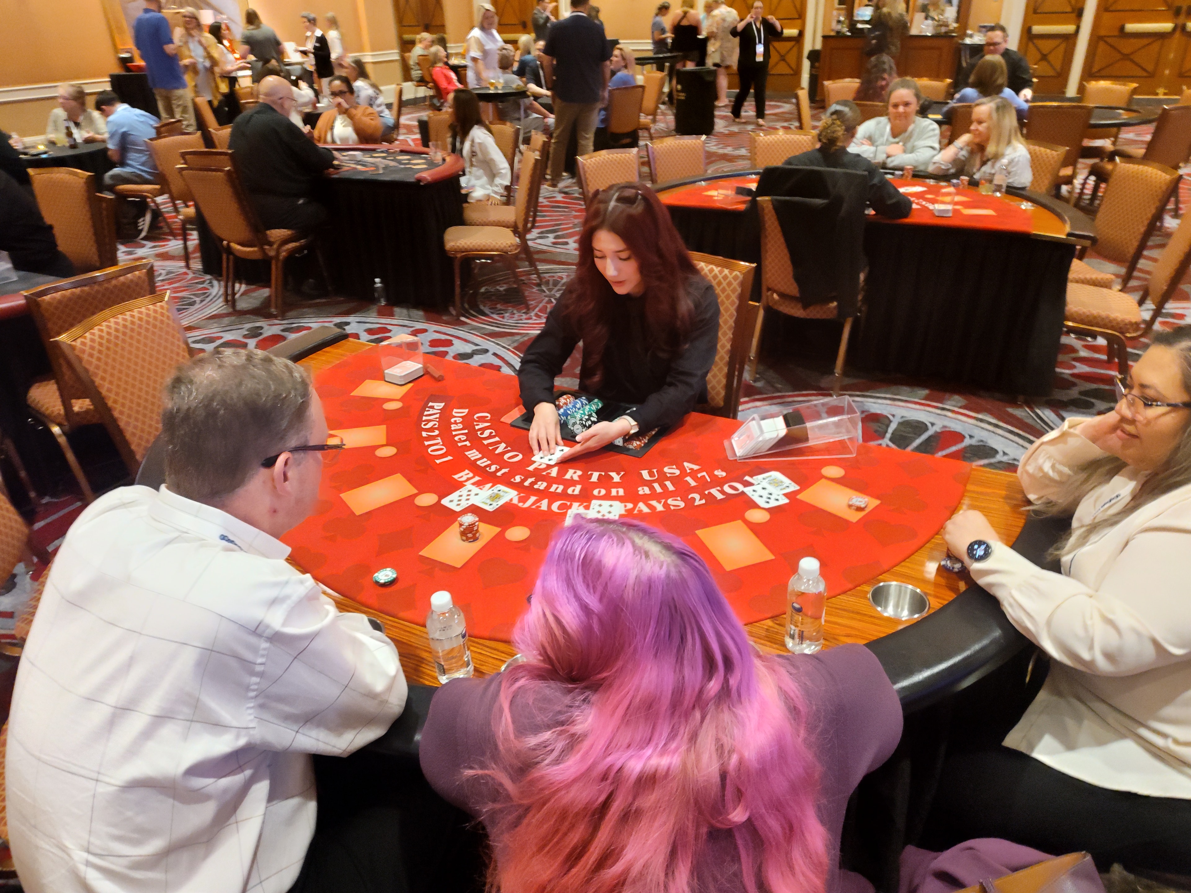 Casino Party USA dealer with red-haired guest at a branded blackjack table in Las Vegas