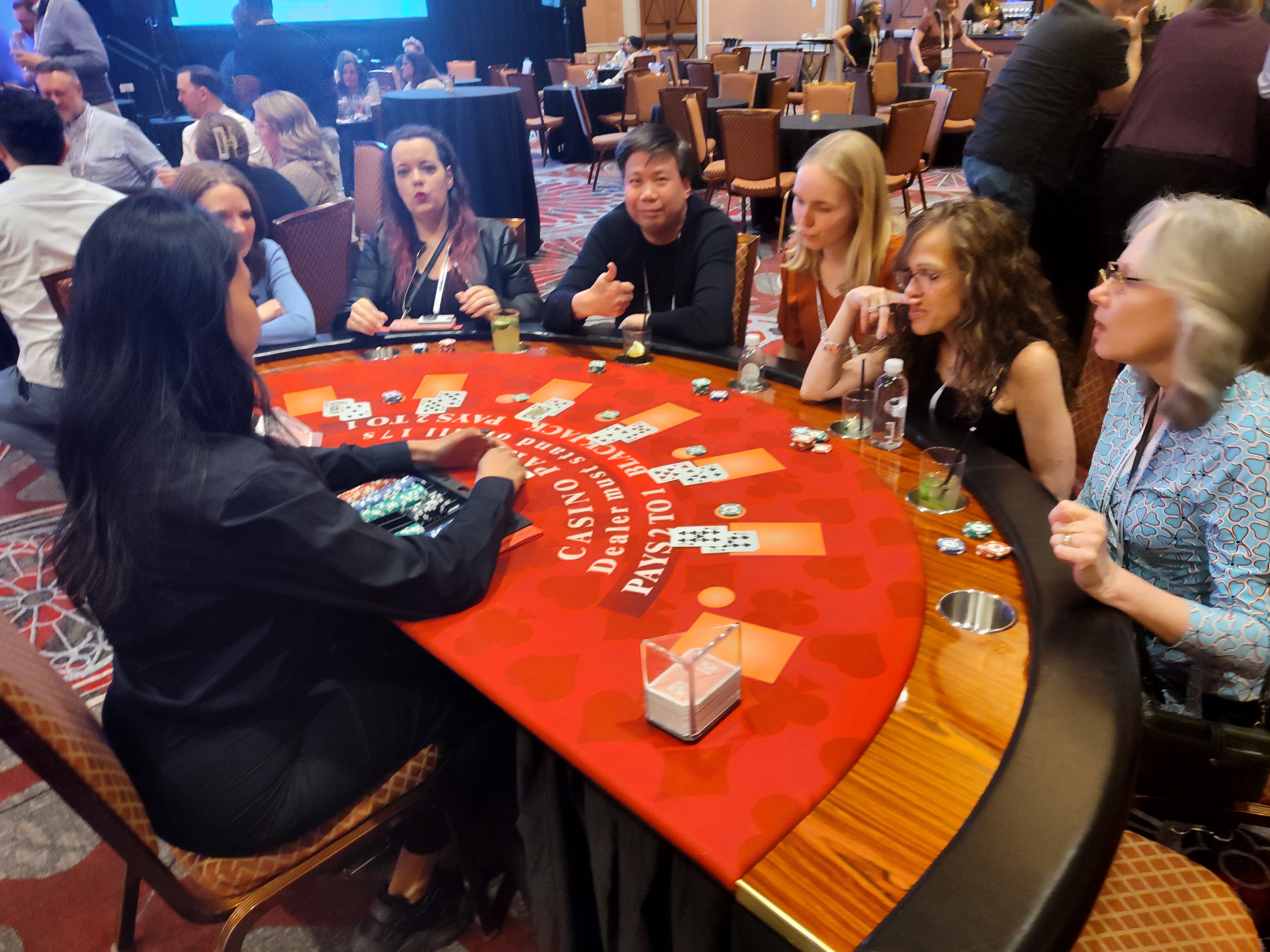Dealer running a Casino Party USA red blackjack table with a full crowd at a Las Vegas event