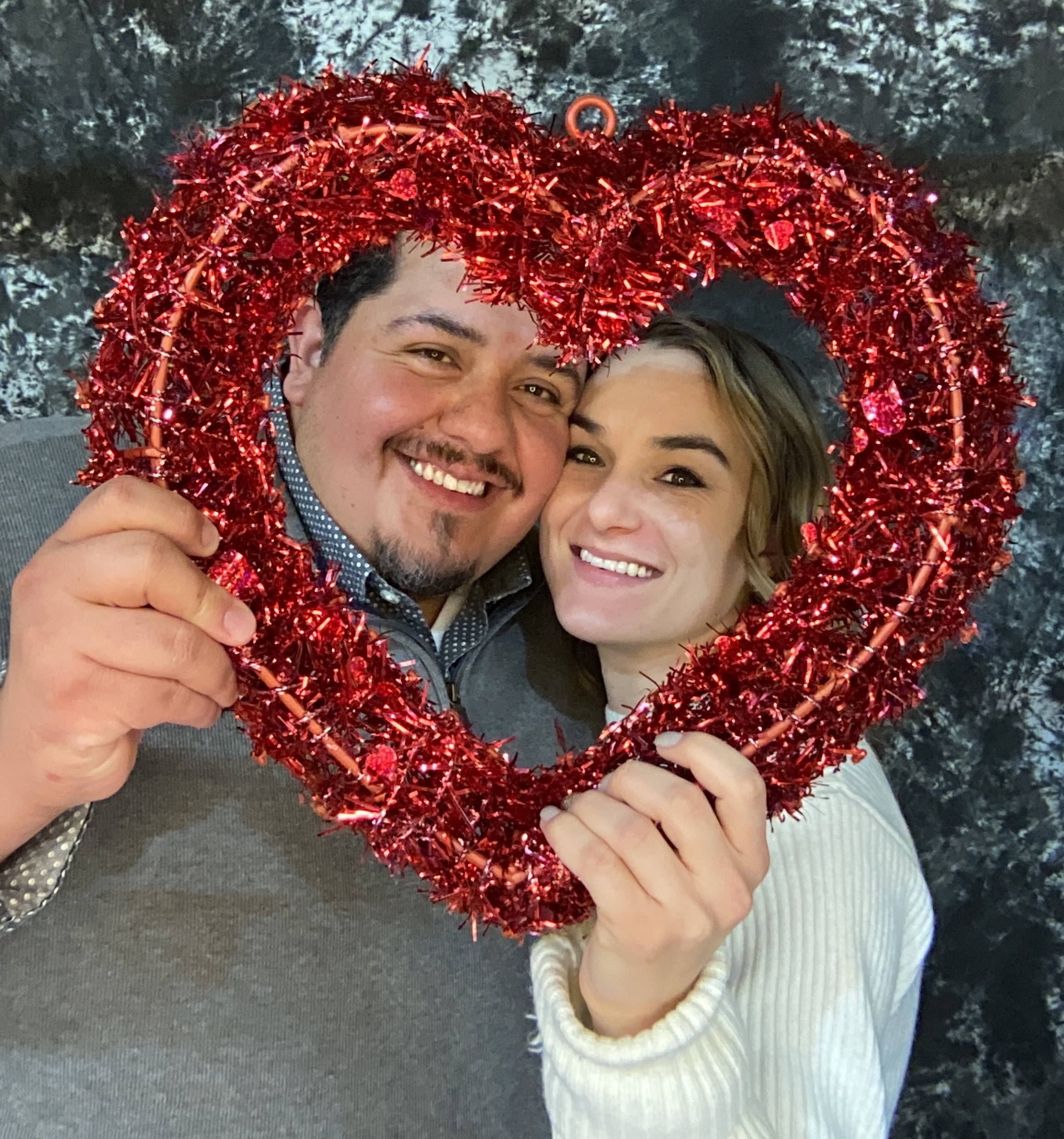 Couple posing with red glitter heart frame prop at Casino Party USA photo booth