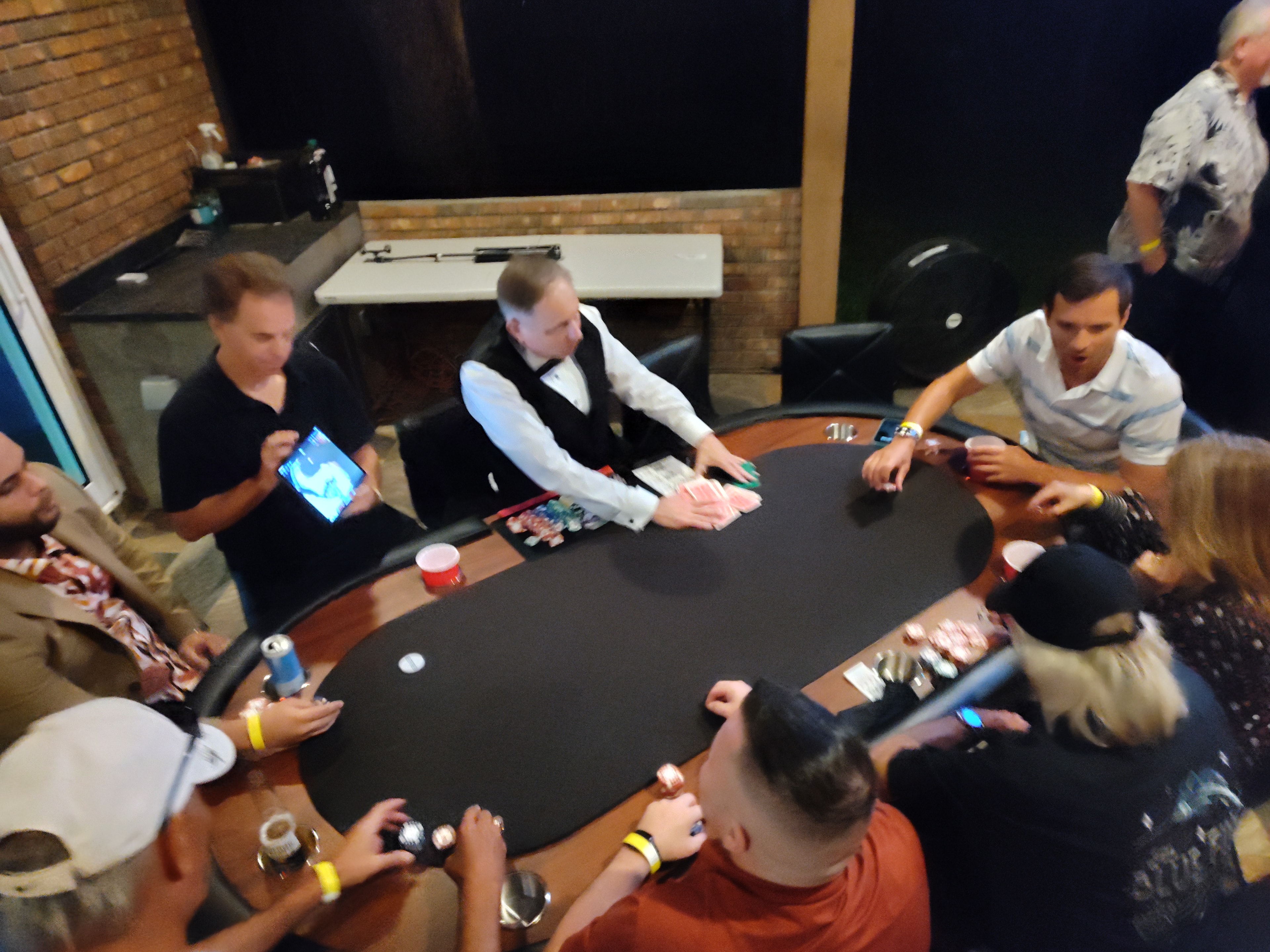 Professional dealer running a poker tournament with a full table of players at a Casino Party USA event