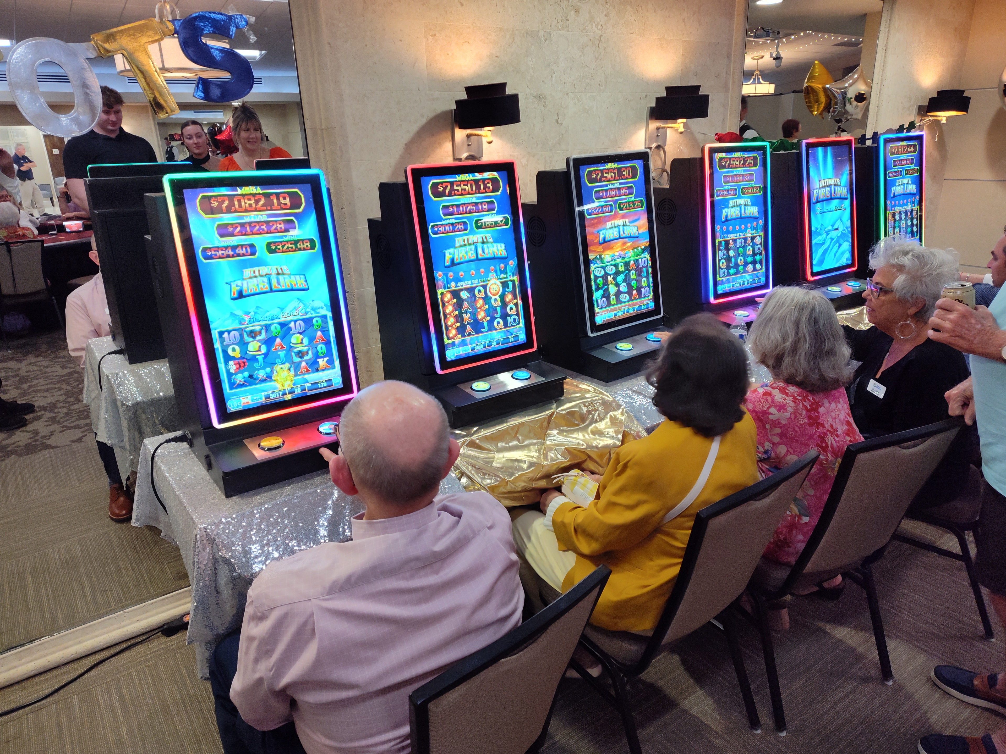 Guests seated and playing Fire Link slot machines at a Casino Party USA event